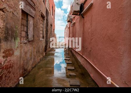 Blick auf das Karibische Meer durch verwitterte rot gestrichene Häuser in Willemstad, Curacao Stockfoto