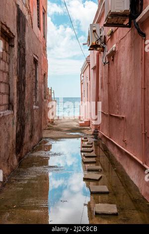 Blick auf das Karibische Meer durch verwitterte rot gestrichene Häuser in Willemstad, Curacao Stockfoto