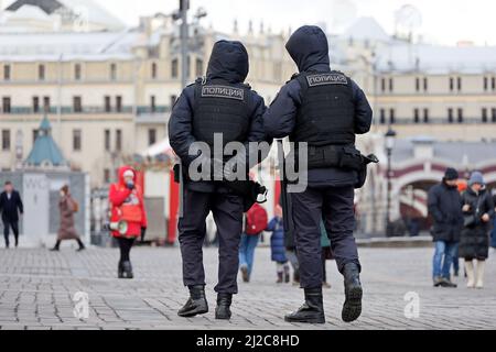 Russische Polizisten in kugelsicheren Westen patrouillieren im Frühjahr auf einer Stadtstraße in Moskau. Übersetzung der Inschrift auf dem männlichen Rücken: 'Polizei' Stockfoto