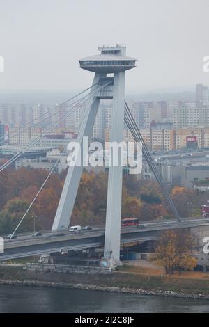 Brücke des Slowakischen Nationalaufstandes (Most Slovenského národného povstania), auch bekannt als SNP-Brücke (Most SNP) über die Donau, entworfen vom slowakischen modernistischen Architekten Jozef Lacko (1967-1972) in Bratislava, Slowakei. Im Hintergrund sind Mehrfamilienhäuser des Stadtteils Petržalka zu sehen. Stockfoto