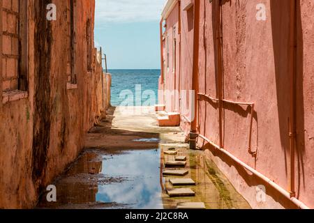 Blick auf das Karibische Meer durch verwitterte rot gestrichene Häuser in Willemstad, Curacao Stockfoto