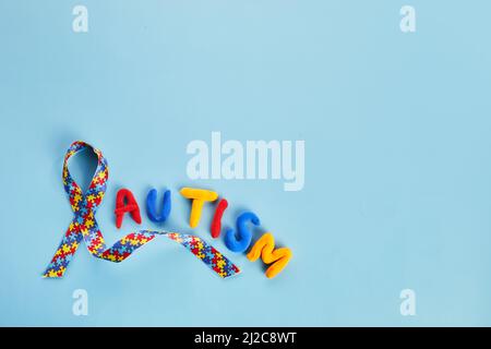 Autismus-Bewusstsein-Konzept mit buntem Band auf blauem Hintergrund. Draufsicht Stockfoto