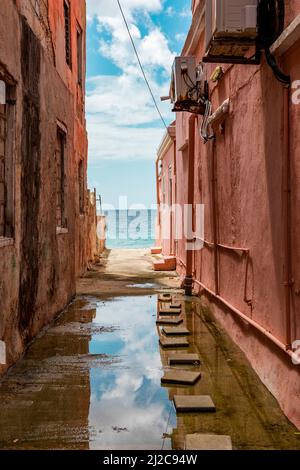 Blick auf das Karibische Meer durch verwitterte rot gestrichene Häuser in Willemstad, Curacao Stockfoto