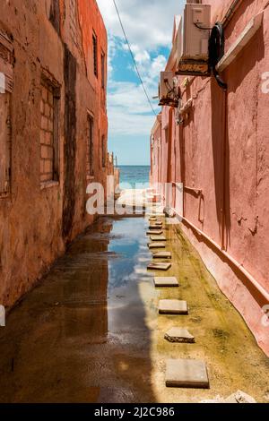 Blick auf das Karibische Meer durch verwitterte rot gestrichene Häuser in Willemstad, Curacao Stockfoto