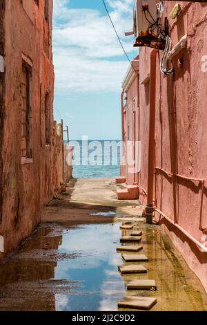 Blick auf das Karibische Meer durch verwitterte rot gestrichene Häuser in Willemstad, Curacao Stockfoto