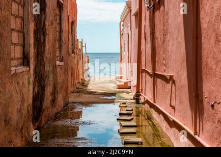 Blick auf das Karibische Meer durch verwitterte rot gestrichene Häuser in Willemstad, Curacao Stockfoto