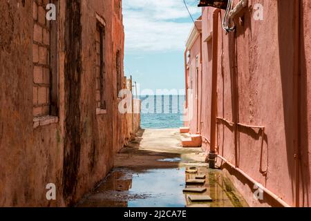 Blick auf das Karibische Meer durch verwitterte rot gestrichene Häuser in Willemstad, Curacao Stockfoto