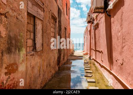 Blick auf das Karibische Meer durch verwitterte rot gestrichene Häuser in Willemstad, Curacao Stockfoto