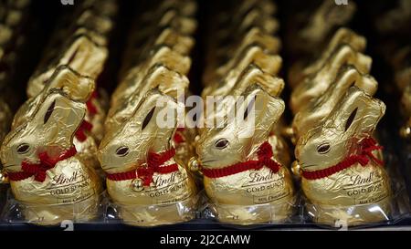 Krakau, Polen, 27. März 2022, Nahaufnahme einer Menge von Schokoladenfiguren von Hasen in Goldfolie auf einem Regal im Laden, Vorbereitung auf den Osterfeiertag.Trad Stockfoto