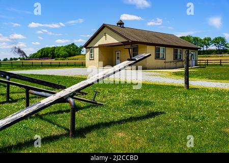 Ronks, PA, USA - 31. Mai 2021: Ein typisches Einzimmer-Amish-Schulhaus im ländlichen Lancaster County. Auf dem Gelände befinden sich Wippsägen und ein modernes Nebengebäude. Stockfoto