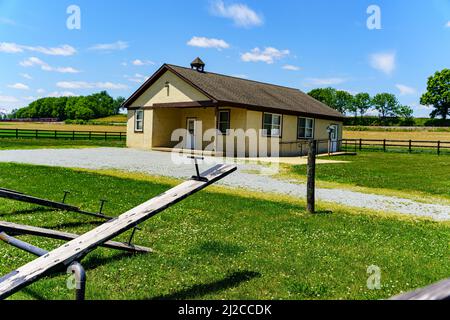 Ronks, PA, USA - 31. Mai 2021: Ein typisches Einzimmer-Amish-Schulhaus im ländlichen Lancaster County. Auf dem Gelände befinden sich Wippsägen und ein modernes Nebengebäude. Stockfoto