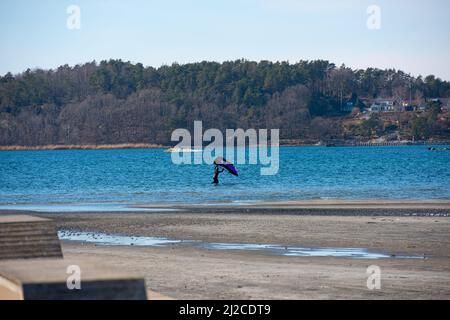 Person im Wasser am Strand, die sich bereit gemacht hat, die Folie zu flügeln Stockfoto