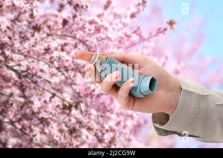 Junge Frau mit Inhalator im Freien am Frühlingstag, Nahaufnahme Stockfoto