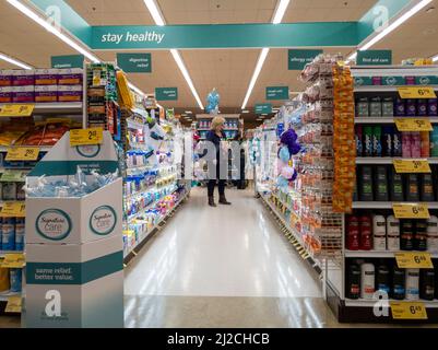 Kirkland, WA USA - ca. Oktober 2021: Frau stöbert in der Apotheke eines Safeway-Lebensmittelladens nach Medikamenten und Nahrungsergänzungsmitteln. Stockfoto