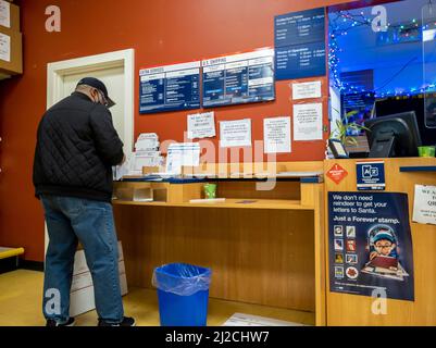 Kirkland, WA USA - ca. Dezember 2021: Schräge Ansicht einer Person, die während der Weihnachtszeit ein Paket bei einem USPS verschiffen hat Stockfoto