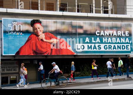 Straßenszene in Havanna, Kuba. Die Menschen kommen an einem wunderschönen Wandbild-Porträt der berühmten kubanischen Sängerin Omara Portuondo direkt unter dem Hotel Havana Libre vorbei. Stockfoto