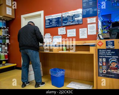 Kirkland, WA USA - ca. Dezember 2021: Schräge Ansicht einer Person, die während der Weihnachtszeit ein Paket bei einem USPS verschiffen hat Stockfoto