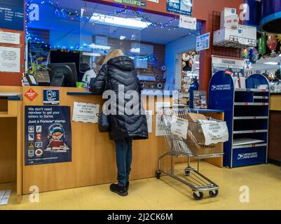 Kirkland, WA USA - ca. Dezember 2021: Schräge Ansicht einer Person, die während der Weihnachtszeit ein Paket bei einem USPS verschiffen hat. Stockfoto