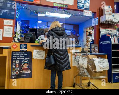 Kirkland, WA USA - ca. Dezember 2021: Schräge Ansicht einer Person, die während der Weihnachtszeit ein Paket bei einem USPS verschiffen hat Stockfoto