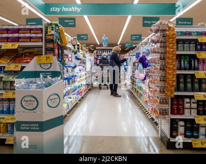 Kirkland, WA USA - ca. Oktober 2021: Frau stöbert in der Apotheke eines Safeway-Lebensmittelladens nach Medikamenten und Nahrungsergänzungsmitteln. Stockfoto