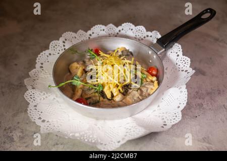 Pfannkuchen mit Pilzen und Kartoffeln in einer Pfanne. Stockfoto