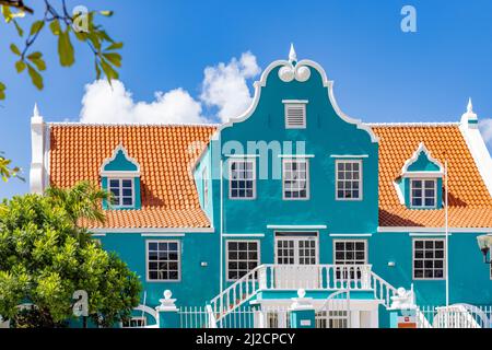 Schönes Gebäude mit türkisfarbener Fassade, weißen Details und einem orangefarbenen Dach in Willemstad, Curacao Stockfoto