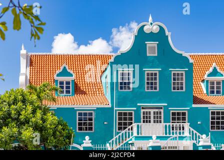 Schönes Gebäude mit türkisfarbener Fassade, weißen Details und einem orangefarbenen Dach in Willemstad, Curacao Stockfoto