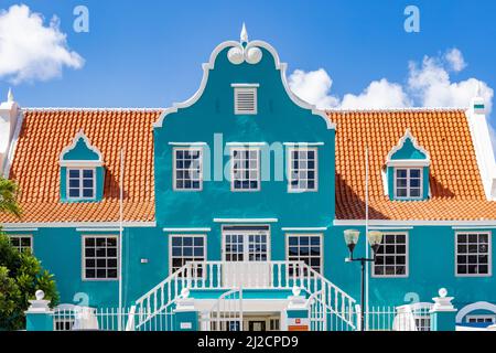 Schönes Gebäude mit türkisfarbener Fassade, weißen Details und einem orangefarbenen Dach in Willemstad, Curacao Stockfoto