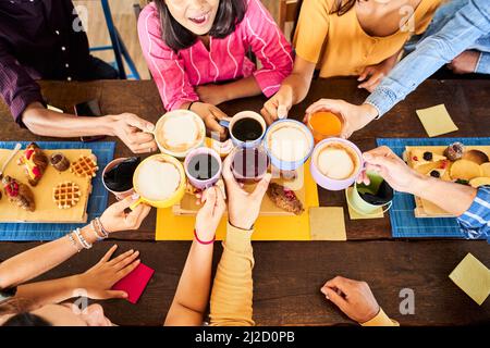 Draufsicht auf Nahaufnahme von multikulturellen Menschen, die beim Frühstück Kaffee und Prost. trinken Fröhlicher Gemeinschaftsspaß in einer Terrassenbar. Stockfoto