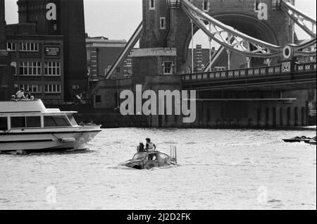 Fernsehmoderator Peter Duncan in einem VW-Käfer-Auto auf der Themse, in der Nähe der Tower Bridge. 10.. Juli 1986. Stockfoto