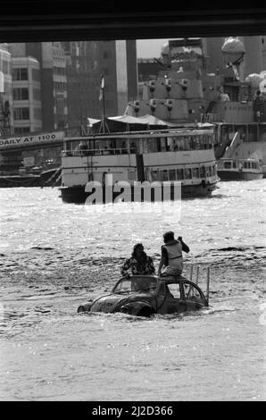 Fernsehmoderator Peter Duncan in einem VW-Käfer-Auto auf der Themse, in der Nähe der Tower Bridge. 10.. Juli 1986. Stockfoto