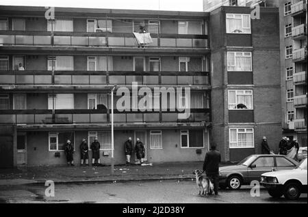 Errol Walker zwang sich am 25.. Dezember 1985 in eine Wohnung im dritten Stock des Poynter Court. Eine Frau taumelte aus und starb später an Messerstichen. Am folgenden Tag umzingelten bewaffnete Polizisten die Wohnungen, in denen Walker die vierjährige Carlene Charles als Geisel hatte. Auf dem Bild wird Carlene von Errol Walker vom Balkon der Wohnungen als Geisel gehalten, die bewaffnete Polizei belagerte darunter. 26.. Dezember 1985 Stockfoto