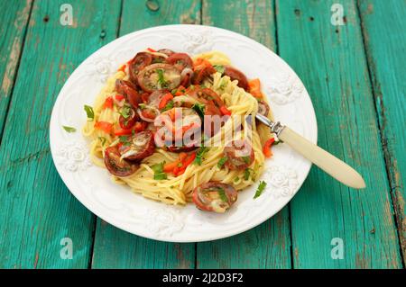 Spaghetti al Pomodoro in weißem Teller mit Gabel auf Holz türkis Tisch horizontal Stockfoto