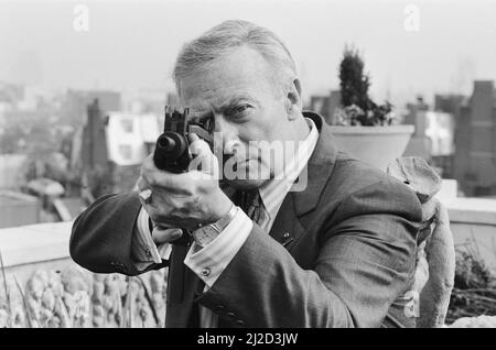 Der britische Schauspieler Edward Woodward, der in der amerikanischen Fernsehserie The Equalizer den Ex-Agenten Robert McCall spielt, posiert in London mit einem Maschinengewehr, um die Serie zu promoten. 25.. Oktober 1986. *** Lokale Bildunterschrift *** Der Equalizer Stockfoto