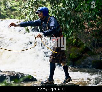 Haltet am Seil fest. Aufnahme eines fokussierten Mannes mittleren Alters, der Schutzkleidung trägt, während er tagsüber ein Seil an jemanden in einem Fluss draußen warf Stockfoto