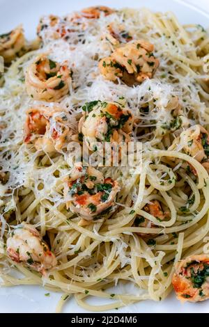 Eine Nahaufnahme von Garnelen-Knoblauch-Pasta mit Parmesan-Käse auf einem weißen Teller Stockfoto