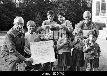 Das Mädchen Zoe Leeper überreicht einen Scheck über £101 von der Mount School, Edgerton, an Herrn Austin Clegg, Ehrenvorsitzender der Yorkshire-Niederlassung des Bleakholt Animal Sanctuary in Ramsbottom, Lancashire. Das Geld wurde durch ein Teddybären-Picknick gesammelt. Ebenfalls abgebildet sind die Kinderlehrerin Frau Yvonne Wheelhouse, die die Veranstaltung organisiert hat, Präfekten und andere Schüler. 11.. Oktober 1985. Stockfoto