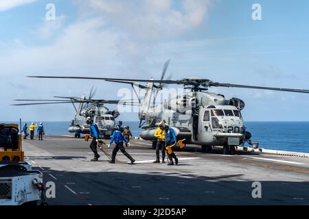 PHILIPPINISCHE SEEFAHRER (14. März 2022), die dem nach vorne eingesetzten amphibischen Sturmschiff USS America (LHA 6) zugewiesen wurden, entfernen während des Routineflugbetriebs Keile und Ketten von einem Super-Hengst-Hubschrauber CH-53E, der der Marine Expeditionary Unit (MEU) von 31. zugewiesen wurde. Amerika, das führende Schiff der America Amphibious Ready Group, arbeitet zusammen mit der 31. MEU im Verantwortungsbereich der US-Flotte von 7., um die Interoperabilität mit Verbündeten und Partnern zu verbessern und als einsatzbereite Einsatztruppe für den Frieden und die Stabilität in der Indo-Pazifik-Region zu dienen. (USA Navy Foto nach Mass Communication Spec Stockfoto