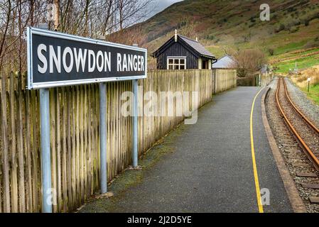 Snowdonia, Wales, UK-March 17. 2022:das Bahnsteigsschild, steht prominent an der kleinen, leeren, walisischen Bergbahnhalt, auf der Route durch Snow Stockfoto