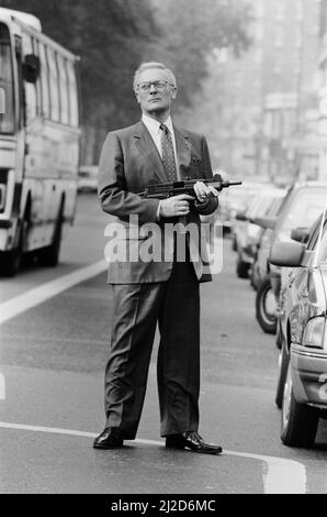 Der britische Schauspieler Edward Woodward, der in der amerikanischen Fernsehserie The Equalizer den Ex-Agenten Robert McCall spielt, posiert in London mit einem Maschinengewehr, um die Serie zu promoten. 25.. Oktober 1986. *** Lokale Bildunterschrift *** Der Equalizer Stockfoto