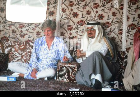 Prinz und Prinzessin von Wales, Naher Osten Tour November 1986. Unser Bild Zeigt ... Prinzessin Diana genießt am Dienstag, den 18.. November 1986, ein arabisches Frühstück mit Prinz Faisal bin Turki in einem Beduinenlager in der Region Ath Thumamah, Wüste, Saudi-Arabien. Trägt eine Tunika aus blau-weißer Seide über Seidentanzügen. Stockfoto