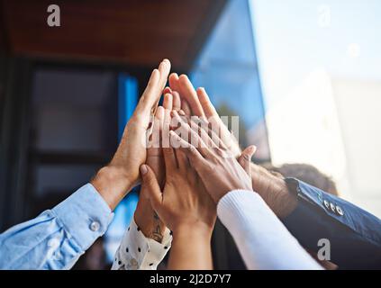 Wir feiern einen weiteren Job Gut gemacht. Eine kurze Aufnahme einer Gruppe von nicht erkennbaren Kollegen, die sich gegenseitig eine hohe fünf gaben. Stockfoto