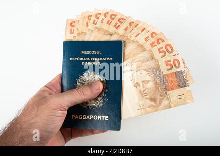Hand hält brasilianischen Pass mit fünfzig reais Banknoten. Brasilianisches Geld. Stockfoto