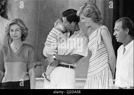 Ihre Königliche Hoheit Prinzessin Diana, die Prinzessin von Wales, und ihr Ehemann, Prinz Charles, der Prinz von Waleson, machen Urlaub in Palma, Mallorca. Sie sind die Gäste von König Juan Carlos (rechts) und seiner Frau Sofia (links) und sind hier im Marivent Palace, Palma, Mallorca abgebildet. Auf diesem Bild hält Prinz Charles einen fast 2 Jahre alten, fast einverletzten Prinz Harry. Bild aufgenommen am 9.. August 1986 Stockfoto