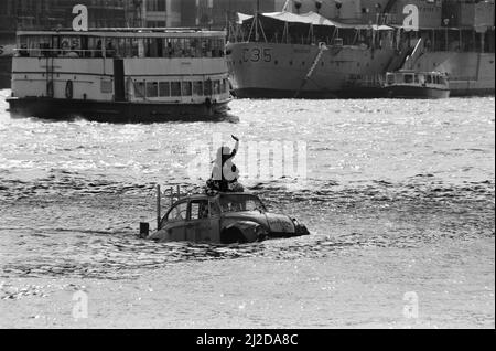 Fernsehmoderator Peter Duncan in einem VW-Käfer-Auto auf der Themse, in der Nähe der Tower Bridge. 10.. Juli 1986. Stockfoto