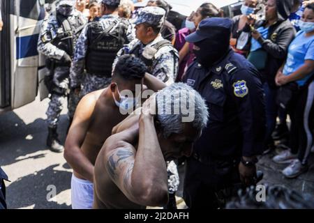 San Salvador, El Salvador. 31. März 2022. Polizeibeamte eskortieren angebliche Bandenmitglieder in ein Haftzentrum. Am Sonntag, dem 27. März, genehmigte der Kongress von Salvadorian den Ausnahmezustand, nachdem das Land seine höchste tägliche Mordrate verzeichnet hatte, mit 62 Tötungen, die aufgrund von Gewalt im Zusammenhang mit Bandenangriffen begangen wurden. Nach Angaben der salvadorianischen Regierung wurden mehr als 3.000 mutmaßliche Bandenmitglieder der Banden MS-13 und Barrio 18 festgenommen. Kredit: SOPA Images Limited/Alamy Live Nachrichten Stockfoto