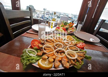 Meerbarsch (türkisch: Barbun) mit Salat und Raki auf dem Restauranttisch. Stockfoto