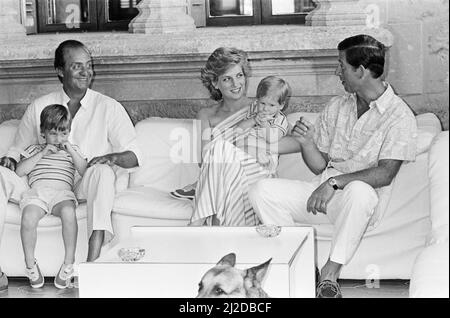 Ihre Königliche Hoheit Prinzessin Diana, die Prinzessin von Wales, und ihr Ehemann, Prinz Charles, der Prinz von Waleson, machen Urlaub in Palma, Mallorca. Sie sind die Gäste von König Juan Carlos (links) und seiner Frau Sofia und sind hier im Marivent Palace, Palma, Mallorca, abgebildet. Auf diesem Bild hält Prinzessin Diana ihren fast 2-jährigen Sohn Prinz Harry. Sein älterer Bruder Prinz William schaut auf König Juan Carlos Schoß. Bild aufgenommen am 9.. August 1986 Stockfoto