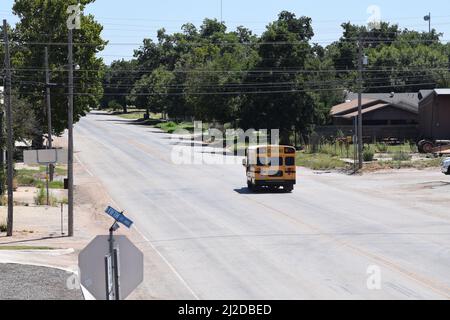Kurzer gelber Schulbus, der eine Straße in Rule Texas entlang fährt - August 2021 Stockfoto