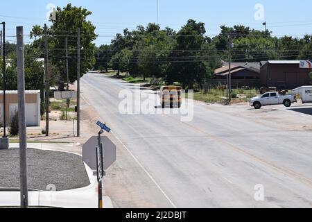 Kurzer gelber Schulbus, der eine Straße in Rule Texas entlang fährt - August 2021 Stockfoto